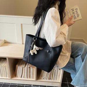 Detailed view of stylish black commuter tote bag with charming horse pendant and shoulder strap.