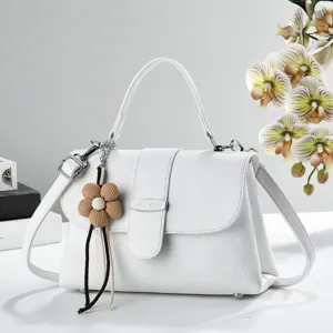 Élégante sacoche bandoulière blanche texturée avec poignée et charmant pendentif fleur.