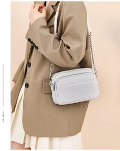 Detail shot of genuine leather crossbody bag with chain strap and soft cowhide texture.