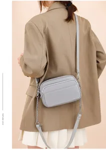 Detail view of the grey genuine leather crossbody bag with chain strap and multi-pocket design.