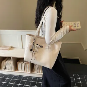 Detail view of a beige PU leather tote bag featuring a chic belt buckle and cute horse charm.