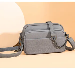 Close-up detail of the grey leather crossbody bag showing the soft texture and metal chain.