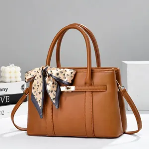 Elegant brown leather handbag featuring a stylish patterned scarf and chic gold-tone lock detail.