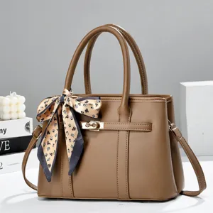 Detailed shot of brown leather handbag with stylish print silk scarf, metal turn-lock closure.