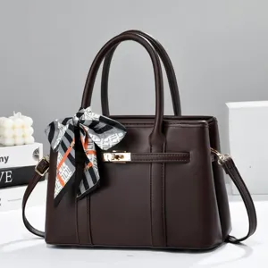 Detailed view of the elegant dark brown handbag with stylish scarf and gold-tone turn-lock hardware.