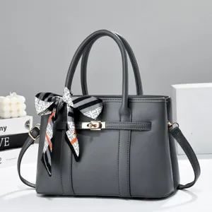 Dark grey women's handbag with top handle, shoulder strap and chic patterned scarf accent.