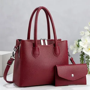 Detailopname van de elegante rode lederen handtas met bijpassend tasje op witte tafel.