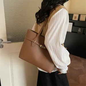 Close-up detail shot of brown leather tote bag showcasing shoulder strap and metallic buckle.