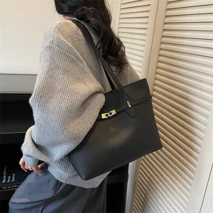 Detailed shot of black leather shoulder tote bag featuring elegant metal lock in scene.