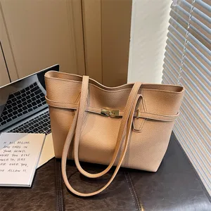 Detailed view of beige leather tote bag, showing delicate metal lock and texture.
