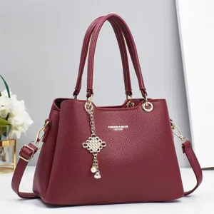 Burgundy leather handbag detail, metal buckle, pearl Chinese knot pendant, premium texture.