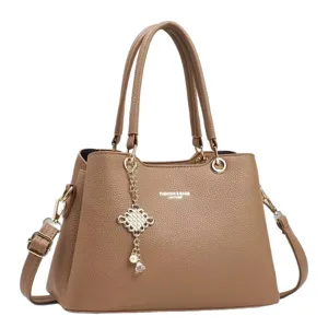 Stylish brown leather handbag for women with top handles and chic charm decoration.