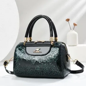 Elegant patent leather boston handbag with floral embossing, top handle and shoulder strap.