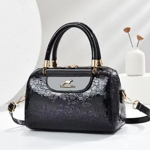 Detailed view of black patent leather embossed floral handbag with gold hardware and dual handles.