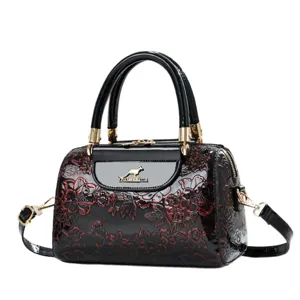 Black patent leather handbag with embossed floral pattern, stylish top handle shoulder bag.