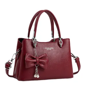 Elegant red leather shoulder bag with chic bow and pearl pendant, classic litchi texture design.