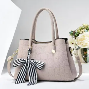 Nahaufnahme der stilvollen grauen Handtasche in Krokooptik mit eleganter Schleife.