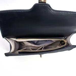 Black women handbag interior detail showing multi compartments zippers and structured lining.