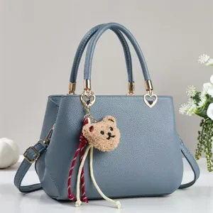 Blue-grey women's handbag with top handle, chic shoulder strap and cute bear plush charm.