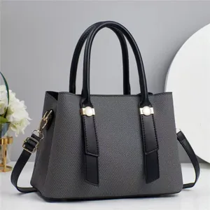 Detailed view of the elegant grey textured women handbag featuring black handles and gold hardware.