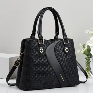 Detail shot of black woven leather handbag featuring dual top handles and adjustable shoulder strap.
