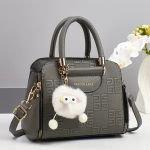 Grey tote handbag detail showing textured embossed geometric pattern and fluffy keyring charm.