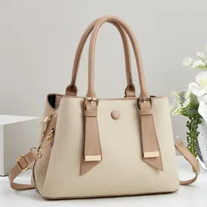 Vista dettagliata della borsa elegante in tela beige con manici in pelle marrone e fibbie metalliche.
