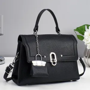 Detailed view of the black leather handbag with silver hardware and chic miniature charm.