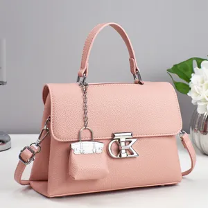 Pink leather handbag for women with top handle, metal lock clasp and cute mini bag charm.
