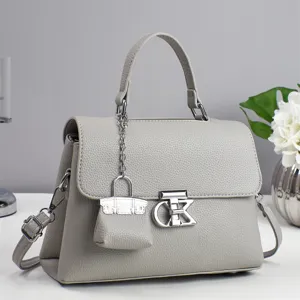 Grey leather top handle handbag with mini charm and metal clasp for women stylish daily use.