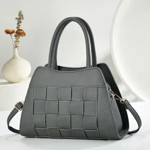 Vue rapprochée du sac à main en cuir tissé gris foncé, mettant en valeur sa texture et détails.