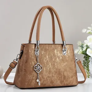 Detailed close-up view of brown textured retro handbag featuring metal clover charm and shoulder strap.