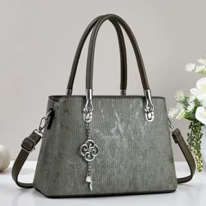 Green women's handbag detail showcasing vintage striped texture, metal handles, and chic charm.