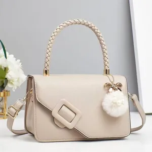 Vue détaillée du sac beige à poignée tressée, mettant en valeur le charm en fourrure et la boucle.