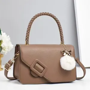 Vue détaillée du sac bandoulière marron doté d'une poignée tressée et d'un pompon.