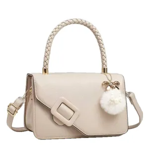 Élégant sac à main beige pour femme avec poignée tressée, grande boucle et joli charm pompon.