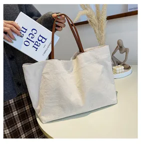 Detailed lifestyle view of large capacity casual canvas tote bag with brown leather handles.