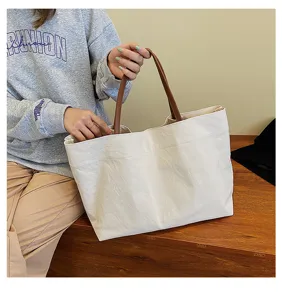 Detailed view of the large capacity canvas tote bag with brown leather handles, casual style.