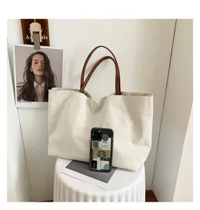 Detailed view of large capacity canvas tote bag with brown leather handles, casual and chic.
