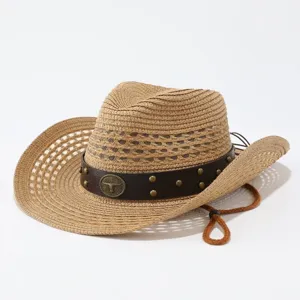 Detalle de sombrero de paja western con cinta de cuero marrón, tachuelas y emblema de toro.