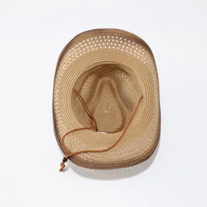 Vista superior de sombrero de vaquero de paja marrón con barbiquejo para sol al aire libre.