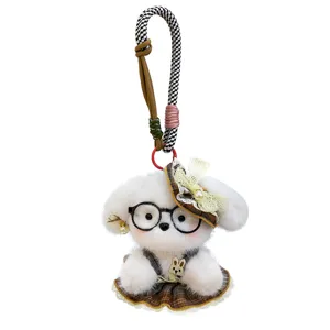 Close-up detail of the cute plush dog keychain featuring black glasses, plaid hat and bow.