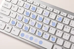 Primo piano dettagliato di simpatici adesivi segnaposto a pois blu su tastiera grigia.