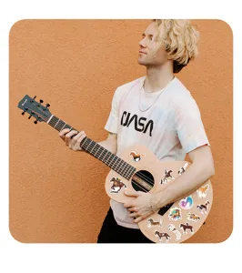 Detailed view of waterproof horse graffiti stickers applied on an acoustic guitar.