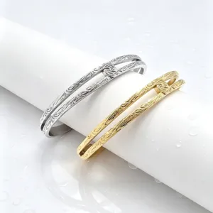 Detail view of double-layer titanium steel Hawaiian vine scroll open cuff bracelets in gold and silver.