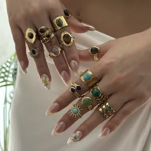 Detailed close-up of stacked gold-plated rings with natural gemstone inlays like tiger eye and turquoise.