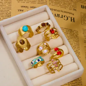 Detailed close-up of vintage multi-stone gold rings set in a soft display tray. Retro jewelry.
