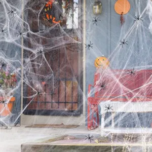 Halloween spider web decoration scene, fake plastic spiders on porch and bench setup.