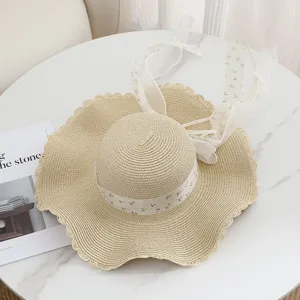 Strohoed met bloemenlint en kant strik, brede golvende rand, elegante Franse strandstijl accessoires.