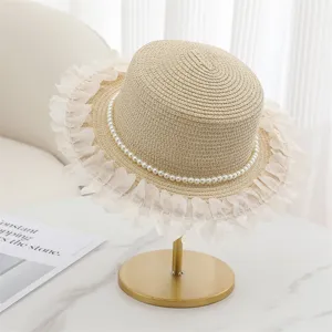 Dettaglio elegante di cappello di paglia piatto con collana di perle e bordo in pizzo bianco estate.